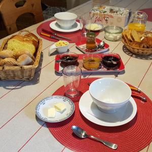 una mesa con platos y cuencos de comida y pan en La Grange Des Roches Roses, en Anchenoncourt-et-Chazel