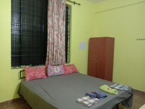 1 dormitorio con cama con almohadas y ventana en Aguiar Guest House, en Colva