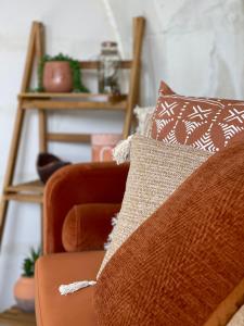 a living room with a couch and a chair with pillows at Le Gîte des Rochettes, 600m à pied du Zoo de Beauval in Saint-Aignan