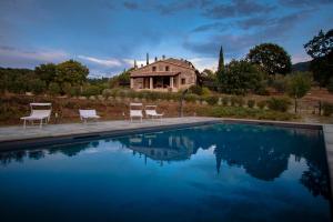 a pool with chairs and a house in the background at Podere Capraia in Castiglioncello Bandini