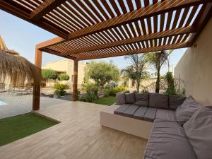a patio with a couch under a wooden pergola at Signorino Suites&Pool in Marsala