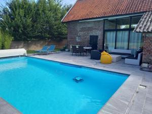 a swimming pool in front of a house at Aux p'tits bonheurs la grange in Neuve-Chapelle