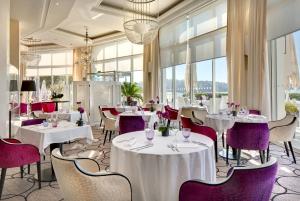 un restaurant avec des tables blanches et des chaises violettes dans l'établissement Grand Hôtel Thalasso & Spa, à Saint-Jean-de-Luz