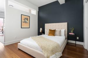 een slaapkamer met een wit bed en een blauwe muur bij Hotel-Apart Prince Arthur in Montreal