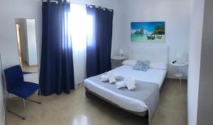 1 dormitorio con cama y cortina azul en Apartamentos Los Banquitos, en Las Eras