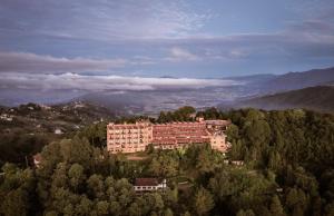 a large building on top of a hill with trees at Club Himalaya, by ACE Hotels in Nagarkot