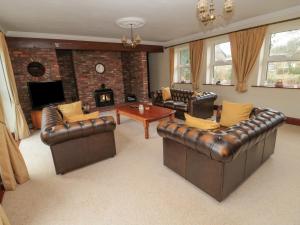 Una sala de estar con muebles de cuero y chimenea. en Barnacre, en Morpeth
