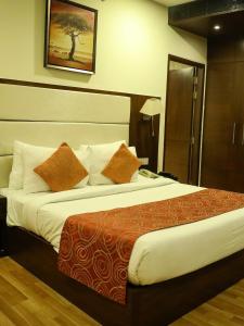 a hotel room with a large bed with orange pillows at Hotel DS Clarks Inn Gurgaon in Gurgaon