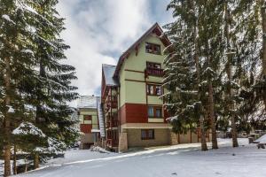 a building in the snow with trees at Wellness Apartmány Fatrapark 1 Malinô Brdo in Ružomberok