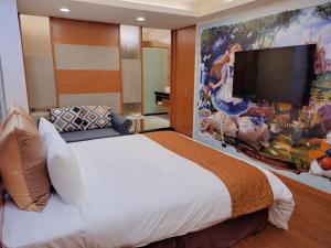 um quarto com uma cama grande e uma televisão grande na parede em Golden Sands Motel em Taoyuan