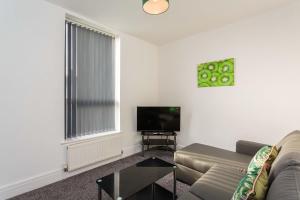 ein Wohnzimmer mit einem Sofa und einem Flachbild-TV in der Unterkunft Cherry Property - Kiwi Suite in Blackpool