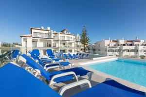 a pool with blue and white lounge chairs and a swimming pool at Correeira Luxury Residence in Albufeira