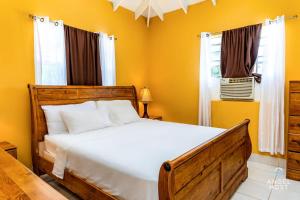 a bedroom with a bed with yellow walls and a window at Chalk Sound Beach Residences Near Sapodilla Bay Beach by Angel Host in Providenciales