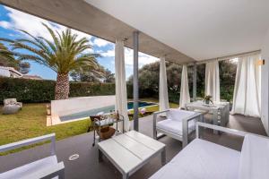 比尼貝卡的住宿－VILLA LA PERLA BLANCA, YOUR DREAM IS TRUE，一个带白色家具和棕榈树的庭院