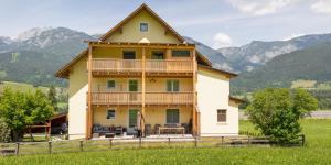 a large house with a balcony and mountains in the background at Appartementhaus Schütter in Haus im Ennstal