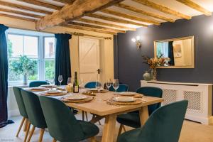 a dining room with a wooden table and green chairs at The Old Post Office by Bloom Stays in Faversham