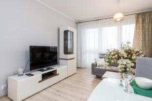 Osiedle Orła Białego Apartament Poznań في بوزنان: غرفة معيشة بيضاء مع تلفزيون وأريكة