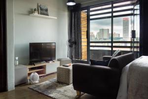 a living room with a television and a large window at Lux Studio Apartment @ Hallmark House in Johannesburg