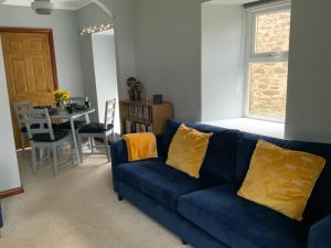 a blue couch with yellow pillows in a living room at The Granary at Tinto Retreats, Biggar is a gorgeous 3 bedroom Stone cottage in Wiston