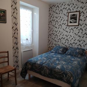 a bedroom with a bed with a blue comforter at Gîte La Hutière près d'Ancenis in Liré