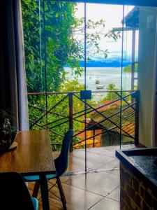 Habitación con mesa y vistas a un balcón. en Casa aluguel Abraão, Vista Mar en Ilha Grande