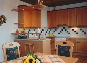 une cuisine avec des placards en bois et une table avec un tournesol dans l'établissement Ferienwohnung Kratochvil, à Bernreith