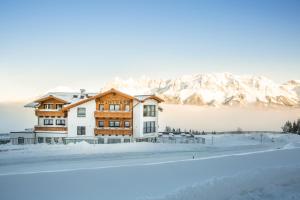 una casa en la nieve con montañas en el fondo en Hotel Winterer en Schladming