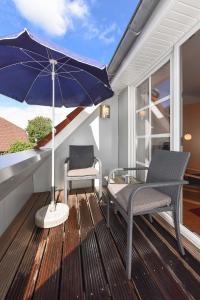 a patio with two chairs and an umbrella on a deck at Ferienwohnung Watt und Weite in Carolinensiel