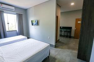 a hotel room with two beds and a table at Vila Castelo Residencial no Centro de Foz in Foz do Iguaçu