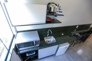 a kitchen with a counter with a sink and a microwave at Vila Castelo Residencial no Centro de Foz in Foz do Iguaçu