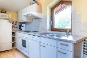 cocina con armarios blancos, fregadero y ventana en Gästehaus Kübler, en Haus im Ennstal