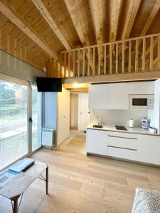 a kitchen with white cabinets and a wooden ceiling at Aloia Nature, Alojamiento Forestal in Tui
