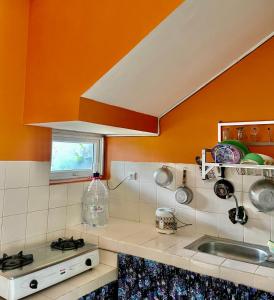a kitchen with an orange wall and a sink at Gerbera 4BR Villa Springhill Garden Malang in Malang