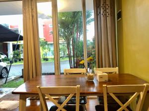 a dining room table with chairs and a large window at Gerbera 4BR Villa Springhill Garden Malang in Malang