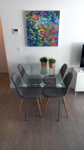 una mesa de cristal y sillas en una habitación con una pintura en Apartamento 1º Línea de Playa - Duna Beach, en Torrox Costa