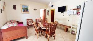 a dining room with a table and chairs and a tv at Residencial Vitoria "Pé na Areia" in Ubatuba