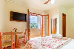 a bedroom with a table and a tv on the wall at Pousada Chaday in Imbituba