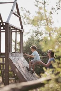 a woman and a child playing on a wooden structure at Toumba Eco Farm Guesthouses in Plomarion
