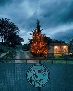 a sign in front of a building with a tree at Toumba Eco Farm Guesthouses in Plomarion