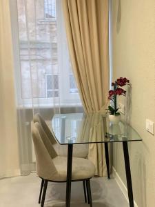 einen Glastisch mit einem Stuhl und eine Vase mit Blumen in der Unterkunft Apart City Home in Mykolajiw