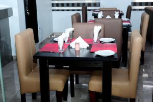 ラゴスにあるMariners Suites Lagosのダイニングルームテーブル(椅子付)、黒いテーブル(赤いナプキン付)