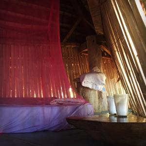 a bed in a room with a red curtain at ENSUEÑOS NATURAL RESERVE Little Corn Island Nicaragua in Little Corn Island