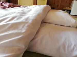 an unmade bed with white sheets and pillows at Tsukechi Bachanchi - Vacation STAY 89810v in Nakatsugawa