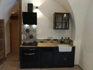 a kitchen with black cabinets and a stove and a sink at Joli petit appartement Montagne#SKI#LAC#NETFLIX# in Seyne