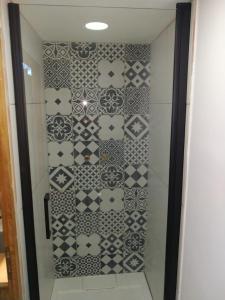 y baño con ducha y azulejos blancos y negros. en Joli petit appartement Montagne#SKI#LAC#NETFLIX# en Seyne