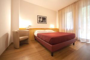 アスコリ・ピチェーノにあるHotel Pennileのベッドと椅子付きのホテルルーム
