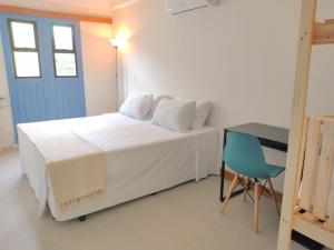 a bedroom with a white bed and a blue door at Pousada VilaZinha in Vila Velha