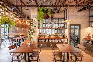 um restaurante com mesas de madeira, cadeiras e plantas em Kokotel Phuket Nai Yang Beach em Nai Yang Beach