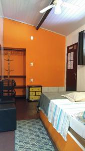 Schlafzimmer mit orangefarbenen Wänden, einem Bett und einer Kommode in der Unterkunft Trip Maresias Suítes in Maresias