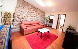 a living room with a red couch and a stone wall at Hotel Boutique Gold Garden in Cusco +37 photos